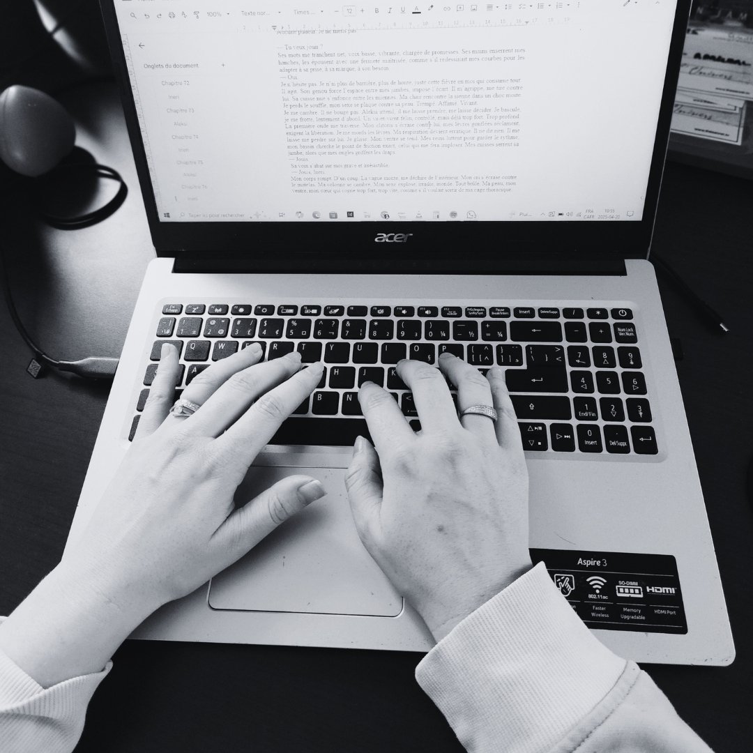 Mains d’Eden James en train d’écrire un roman sur son ordinateur portable. Auteure de romance spicy.